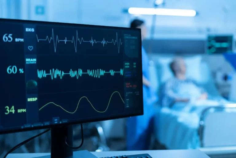 A computer monitor displaying vital signs like EKG heart rhythm and brain activity in a hospital room.